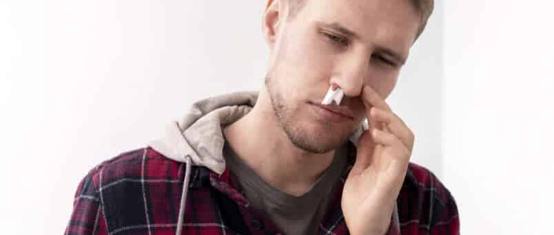 a man holding his coke nose that is bleeding