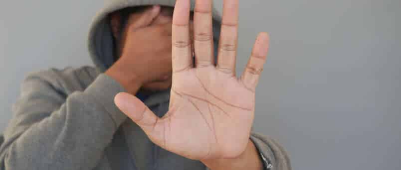 a hooded man covering his face sores from drugs