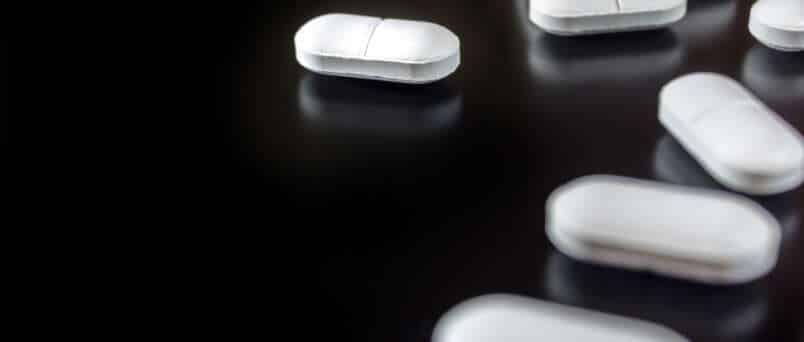 white pills on a black background begging the question "can hydrocodone cause anxiety?"